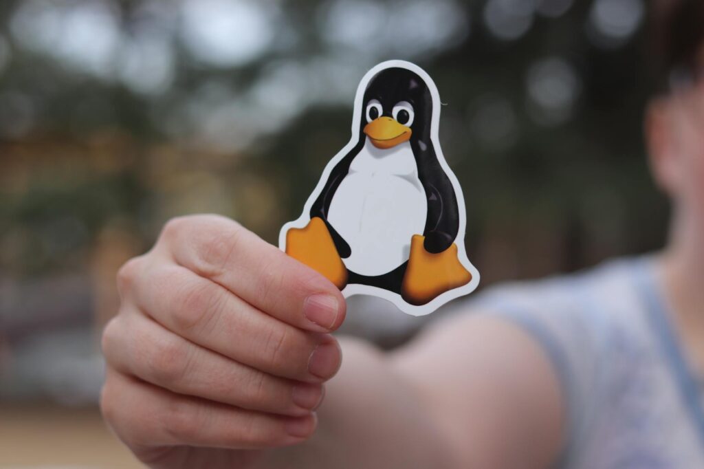 a person holding black and yellow penguin sticker